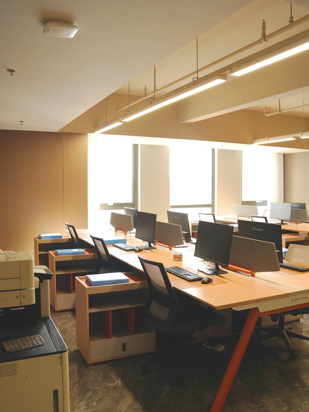 Interior de oficina moderna con escritorios de madera y grandes ventanales.