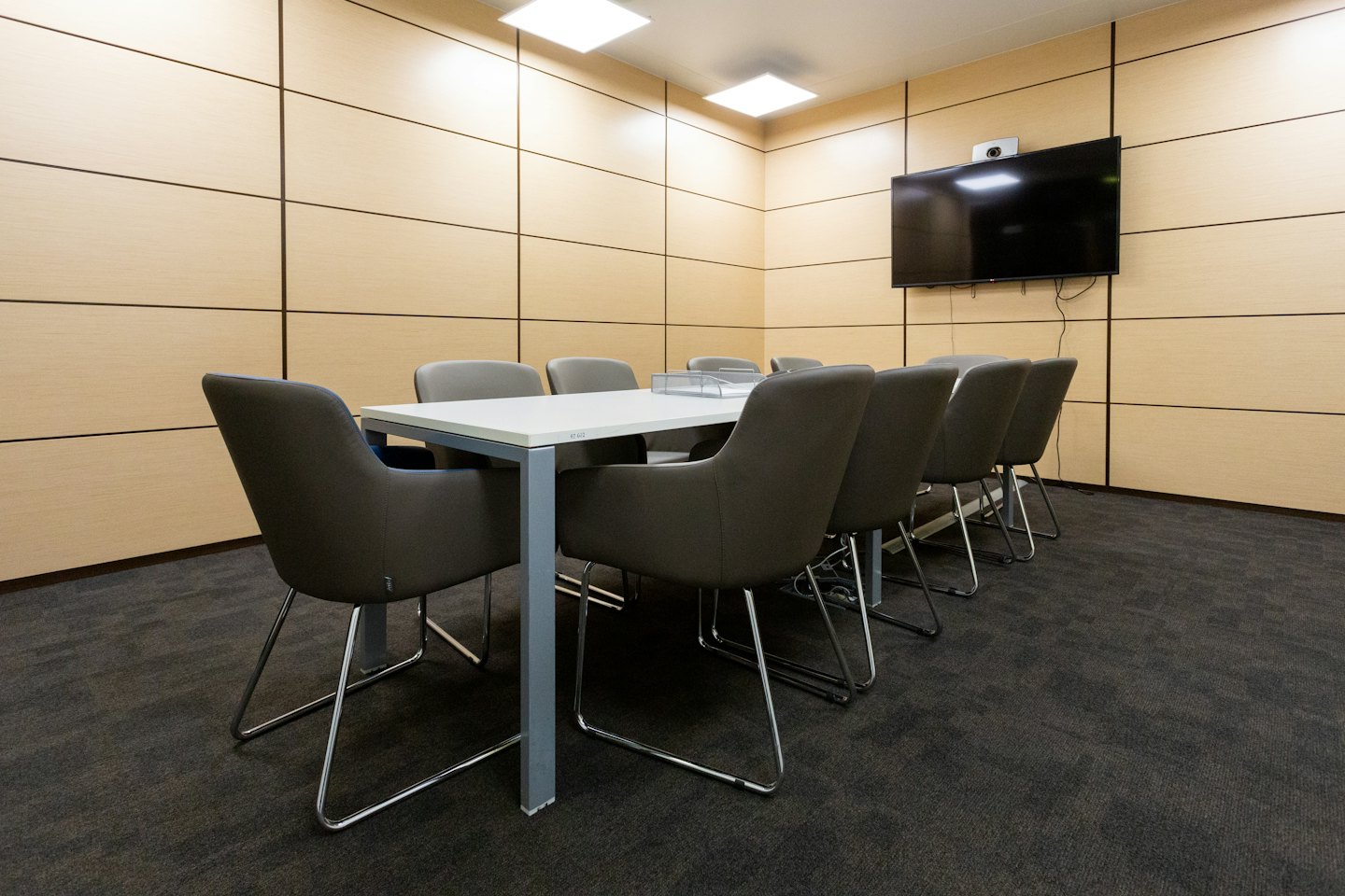Sala de conferencias moderna con mesa grande y ocho sillas.