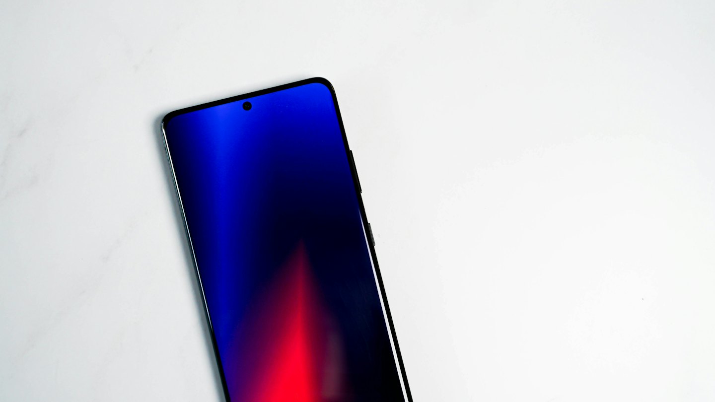 Un moderno smartphone con pantalla colorida descansa sobre mármol blanco.