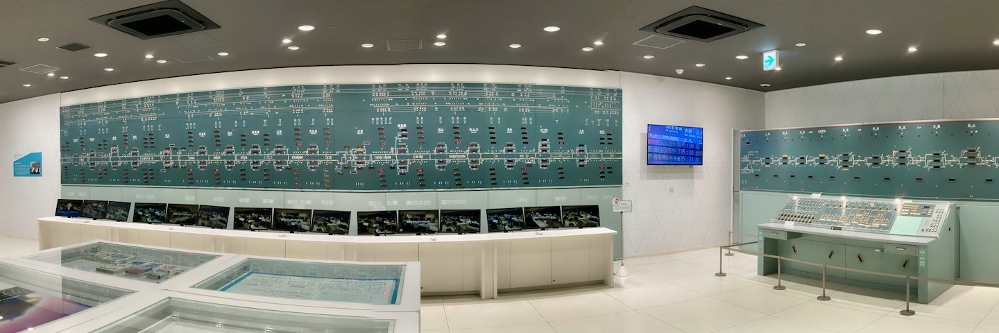 Sala de control de trenes moderna con monitores y un gran diagrama de vías.